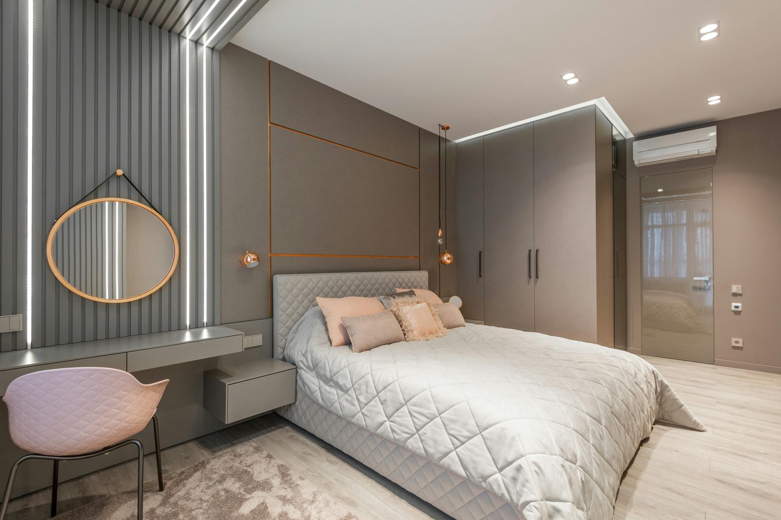 Built-in dressing table with round mirror and pendant lighting against a fluted feature wall