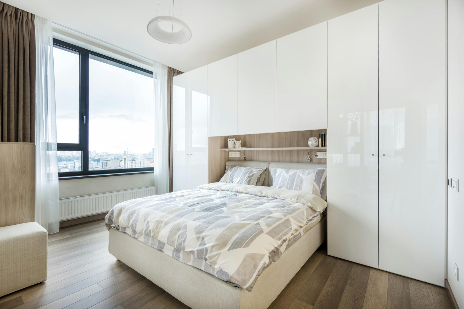 High-gloss white sliding-door wardrobes alongside a calm neutral bedroom