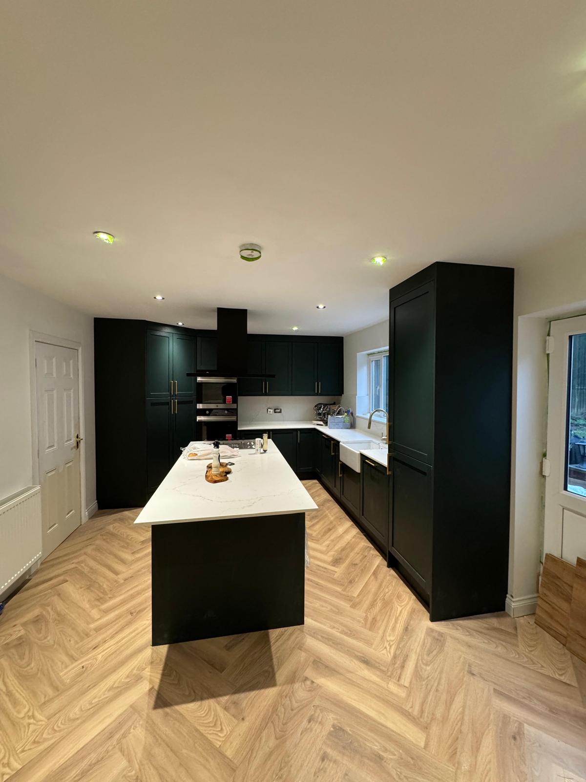 Dark green shaker kitchen with white quartz island and herringbone floor